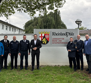 Eine Gruppe von neun Personen stehen vor dem Tor des Landesamtes für Brand- und Katastrophenschutz.